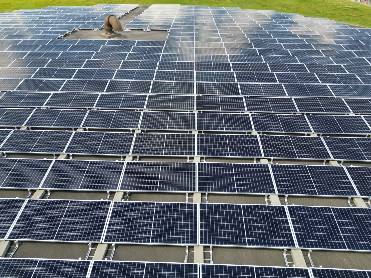 services-02 A large solar panel array on a sunny day in an open green field.